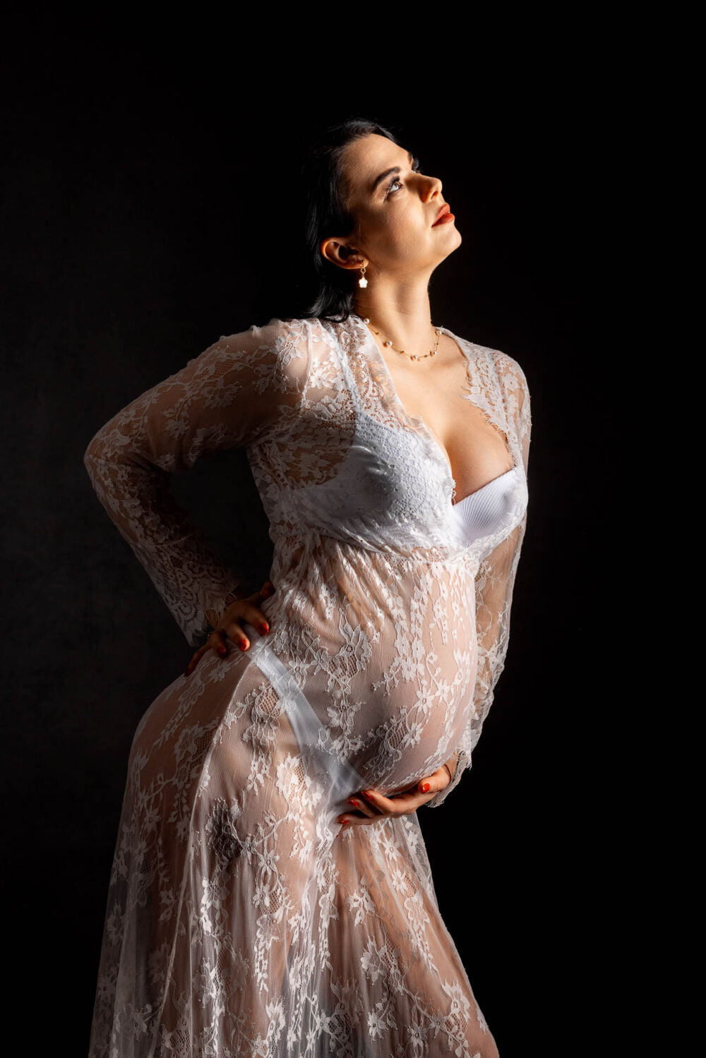Minimalistyczne zdjęcie ciążowe w studio, pokazujące sylwetkę przyszłej mamy w konturze, z akcentem na piękną linię brzuszka