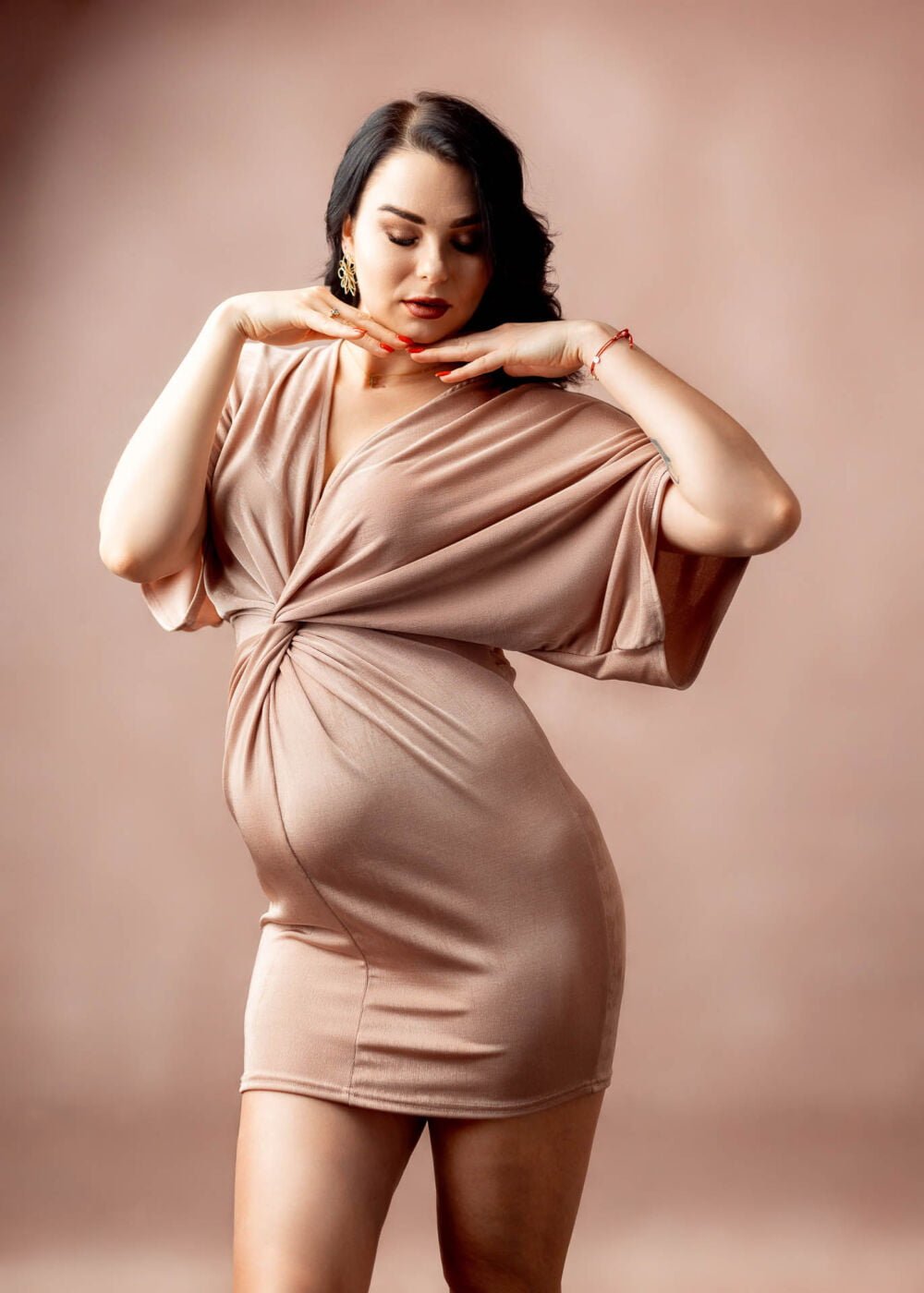 Czarująca sesja ciążowa w studio, z przyszłą mamą ubraną w stylową, koronkową suknię, podkreślającą piękno jej sylwetki