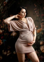 Portret ciążowy z Słupska ukazujący przyszłą mamę w naturalnym świetle, uchwyconą w momencie czułego dotyku do zaokrąglonego brzuszka
